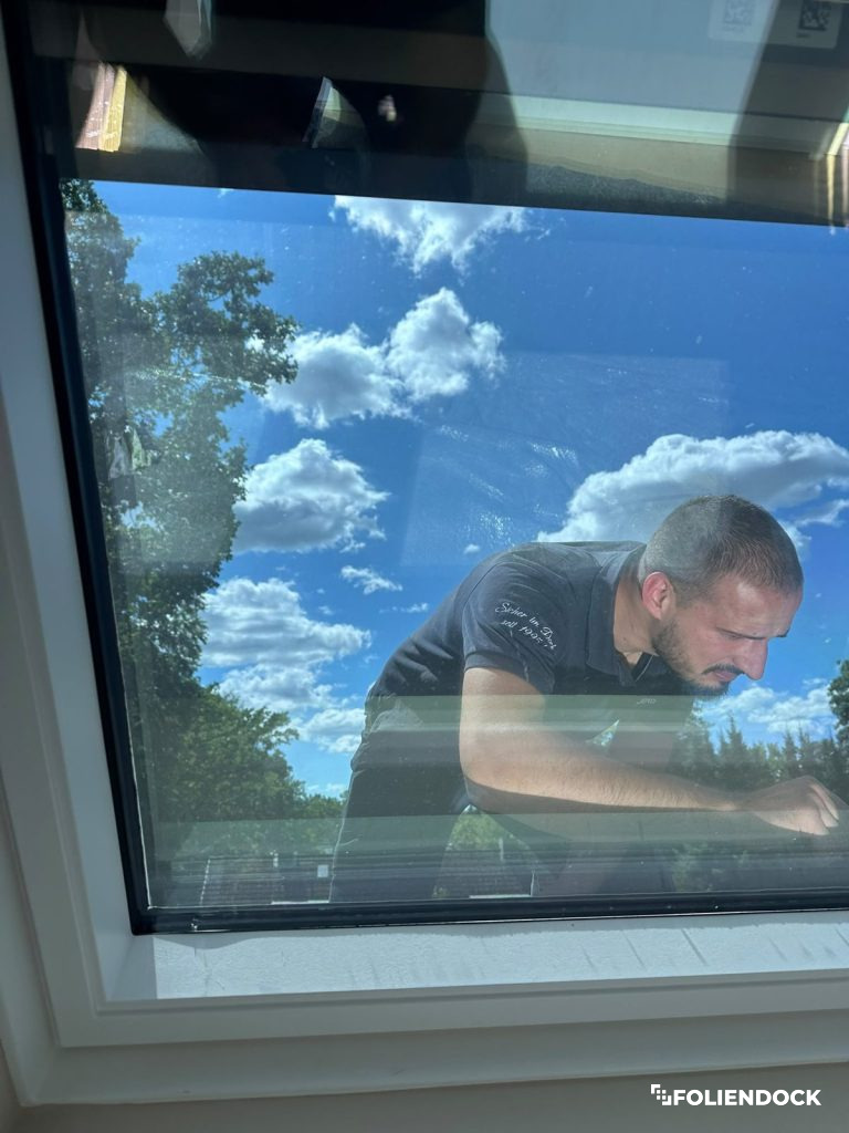 FolienDock Monteur bei der Außenmontage von Sonnenschutzfolie am Dachfenster