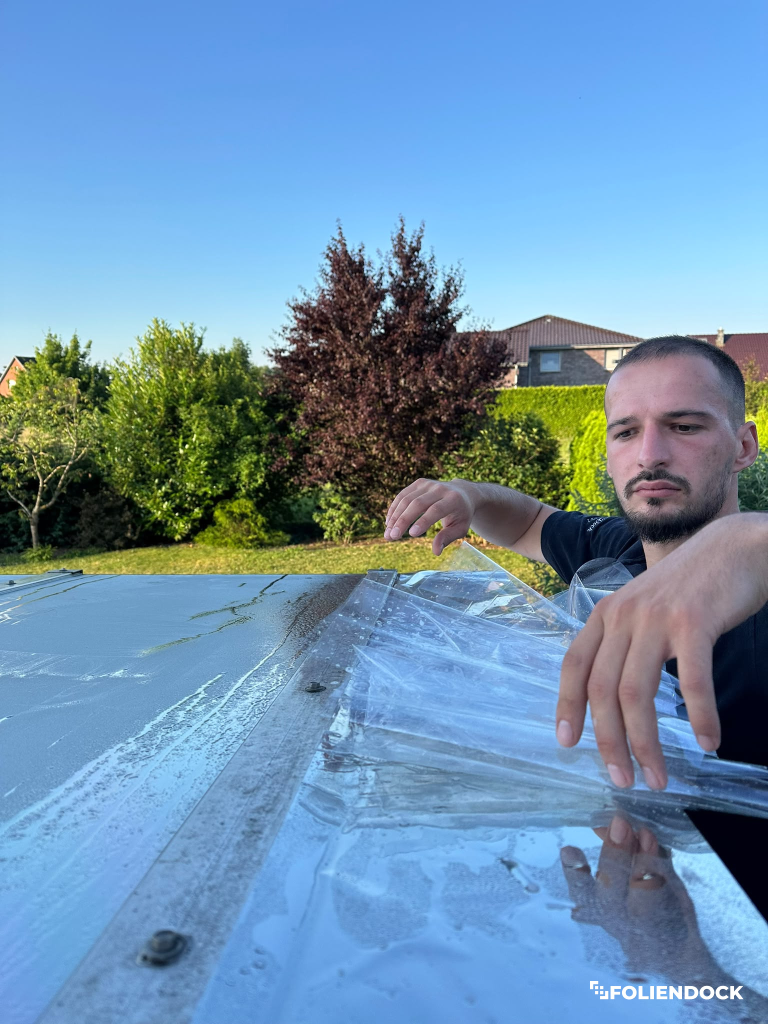 Alte Fensterfolie wird von einem Glasdach abgezogen, PurDock